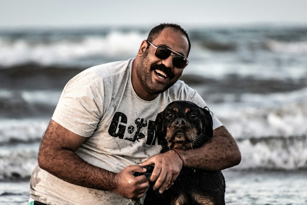 a man sitting on the beach with a dog